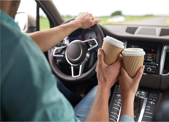 Image of a couple in a car toasting with two takeout coffee cups